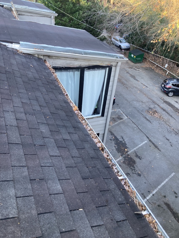 Gutter along a multi-unit property roofline packed with fallen leaves before cleaning